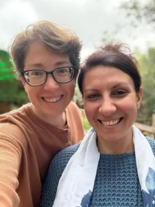 uma mulher de óculos e cabelo curto ao lado de uma mulher com um coque no cabelo