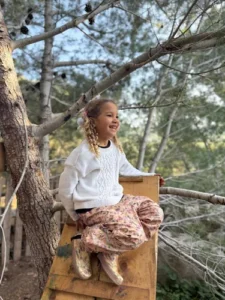 criança de jumper branco numa rampa de escorregar pikler