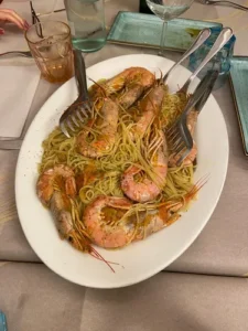 um spaghetti com camarão em um prato e uns talheres