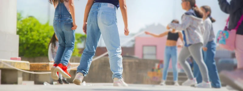 Crianças pulando corda em um ambiente alegre, ilustrando a fase lúdica da infância que pode ser comprometida pela exposição precoce a músicas com conteúdo sexualizado.